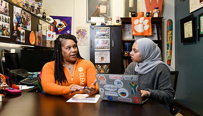 Two women in a conversation while looking at a laptop