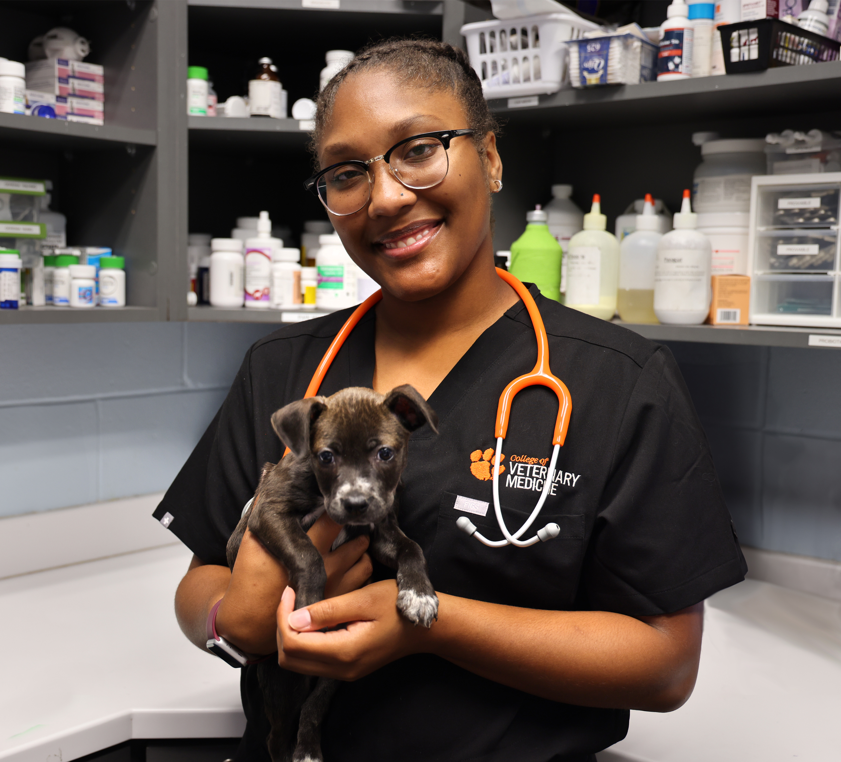 Student in scrubs holding a puppy.